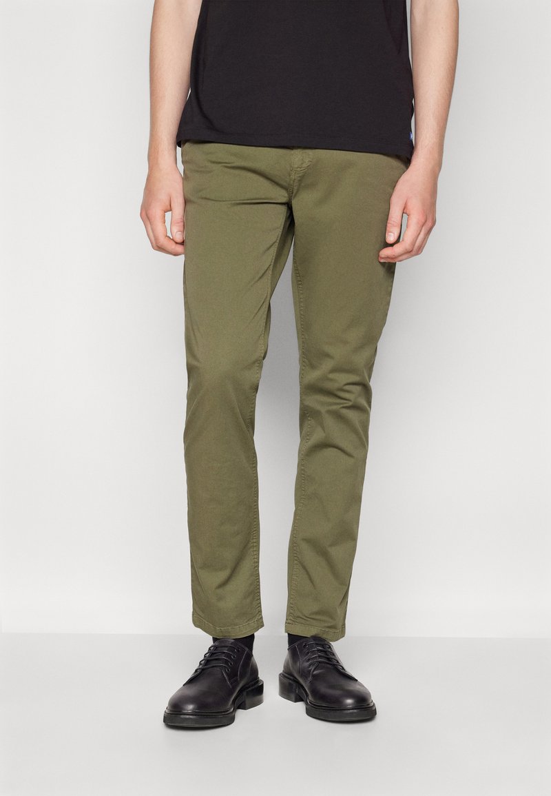 Chinos verde oliva con vestibilità slim, caratterizzati da una texture liscia e design a cinque tasche, abbinati a scarpe nere stringate.