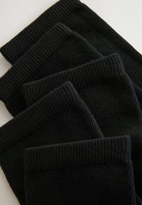 Vier Paare schwarze gerippte Socken gestapelt, die dicke Stricktextur und elastische Bündchen für einen sicheren Sitz zeigen.