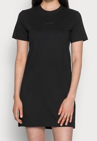 Svart bomulls t-shirtklänning med korta ärmar, rundad halsringning och rak skärning. Har en subtil Calvin Klein jeans-logotyp på bröstet.