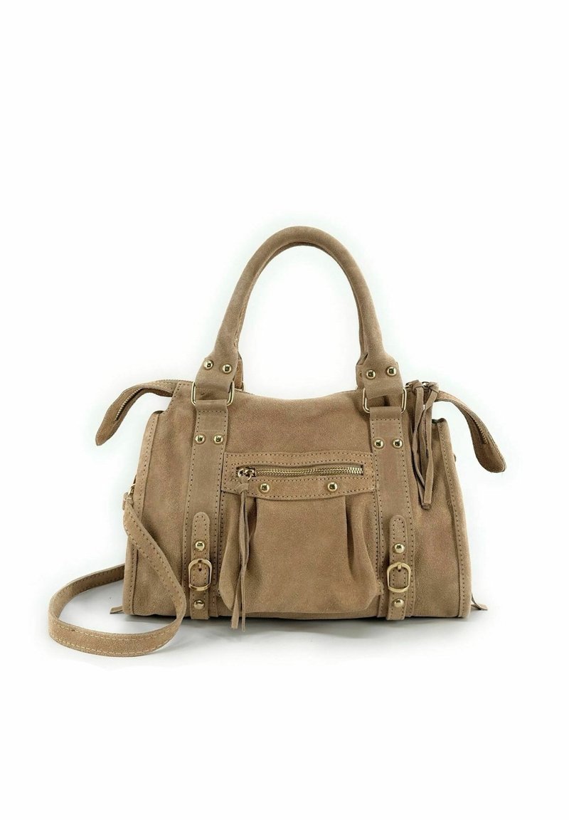 Sac à main en daim beige avec double poignée, bandoulière réglable, poche avant zippée, garnitures dorées et pompons sur les côtés. Design compact et structuré.