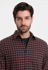 Camicia a quadri in arancione e blu navy, con design button-up, colletto e taschino sul petto. Il tessuto sembra morbido con una leggera texture.