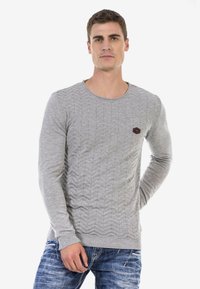 Grauer Langarmpullover mit strukturiertem Zickzackmuster. Verfügt über einen runden Ausschnitt und ein kleines, dunkles Logo auf der Brust.