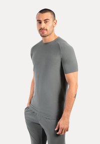 Grijze sport T-shirt met korte mouwen, een ronde halslijn en een gladde textuur, gecombineerd met bijpassende broek voor een gecoördineerde look.