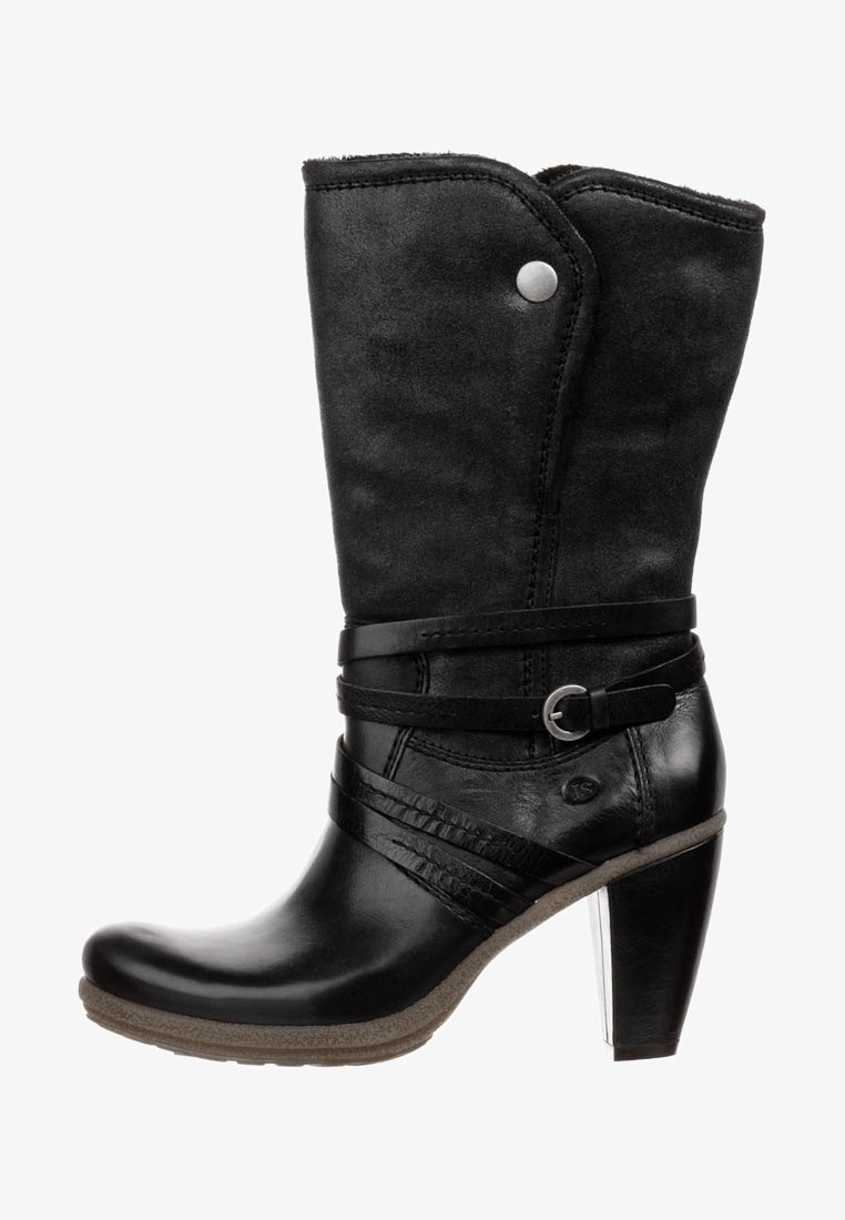 Musta nahkainen nilkkuri, jossa on mokkanahkainen päällinen, koristeelliset remmit, hopeanväriset metalliosat ja paksu korko. Nahan pintakuviointi antaa tekstuuria.