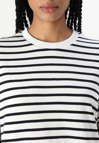 Black and white striped short-sleeve top with a ribbed crew neckline. Fabric appears soft with a smooth texture and consistent stripe pattern.