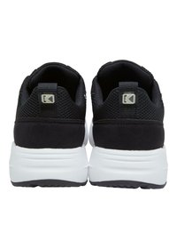 Baskets de sport noires avec une tige en maille et un col rembourré, dotées d'une semelle intermédiaire blanche et d'une semelle extérieure noire texturée, affichant un logo sur le talon.