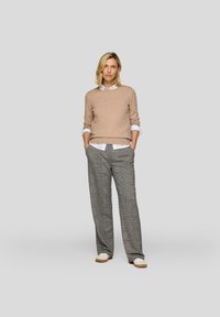 Beiger Pullover, darunter ein weißes Hemd mit Kragen, graue und schwarze karierte weite Hose und hellfarbige Schuhe. Einfache Designelemente.