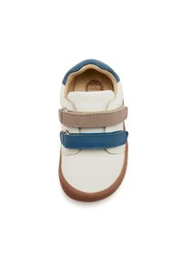 Zapatilla blanca con correas de velcro azul y marrón, suela de goma marrón y parte superior de cuero suave. Presenta una puntera redondeada y un collar acolchado.