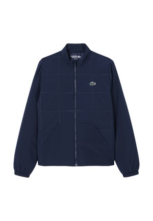 Veste zippée bleu marine avec coutures en quadrillage, poignets élastiques, deux poches avant et un petit logo crocodile vert sur la poitrine.