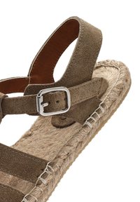 Sandalo in suede marrone con suola in juta intrecciata, cinturino regolabile con fibbia in argento e superficie testurizzata sulla parte superiore.