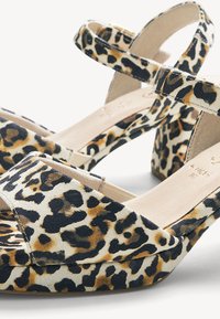 Sandales à talons épais avec brides à la cheville et motif léopard en beige, noir et tons marron.
