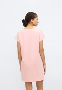 Ροζ βαμβακερό φόρεμα με κοντά μανίκια, άνετη γραμμή, μήκος μέχρι το μέσο του μηρού, στρογγυλή λαιμόκοψη και λείο ύφασμα. Ορατή ραφή στα τελειώματα.