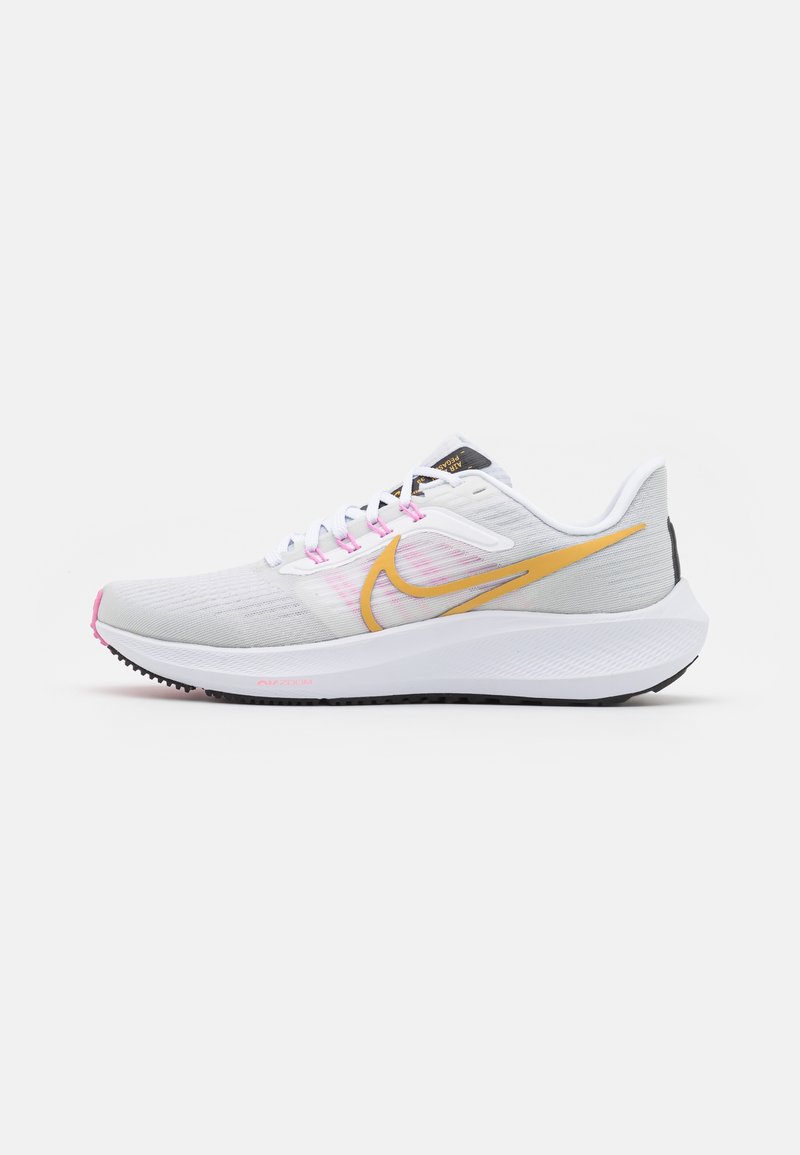 Chaussures de course blanches avec une tige en mesh léger, des accents jaunes et roses, un col rembourré, une semelle amortie et une semelle extérieure en caoutchouc noir texturée.