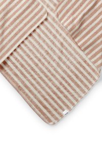 Randig badmatta i mjuk frotté, med växlande ljusbeige och persikofärgade ränder, samt ett vitt märke i det nedre hörnet.