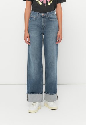 Vidde jeans i lyseblått med brettes grå buksekant. Har tradisjonelle lommer og knappelukking. Kombinert med hvite sneakers.