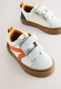 Hellfarbene Leinwand-Sneakers mit grauen Klettverschlussriemen, orangefarbenen Akzenten, brauner Gummisohle und gelbem Innenfutter mit Sonnen- und Berggrafiken.