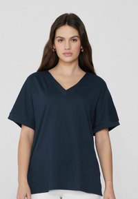 Námořnická modrá v-neck tričko vyrobené z měkké látky, krátké rukávy, volný střih, s ohrnutými manžetami a hladkým povrchem.
