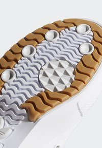 Suela de zapatilla blanca con un diseño texturizado, patrones de tracción de goma, acentos circulares elevados y un elemento central angular.