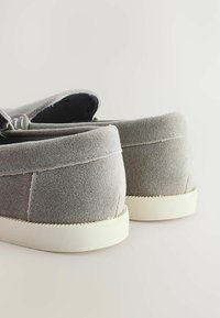 Graue Wildlederschuhe zum Slip-On mit weicher Textur, runder Form und weißen Gummisohlen, minimaler Nahtführung und ohne sichtbare Akzente.