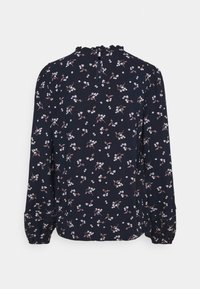 Marinblus med blommönster och långa ärmar, med en strukturerad, volangkrage och knappstängning bak. Små vita och rosa blommor.