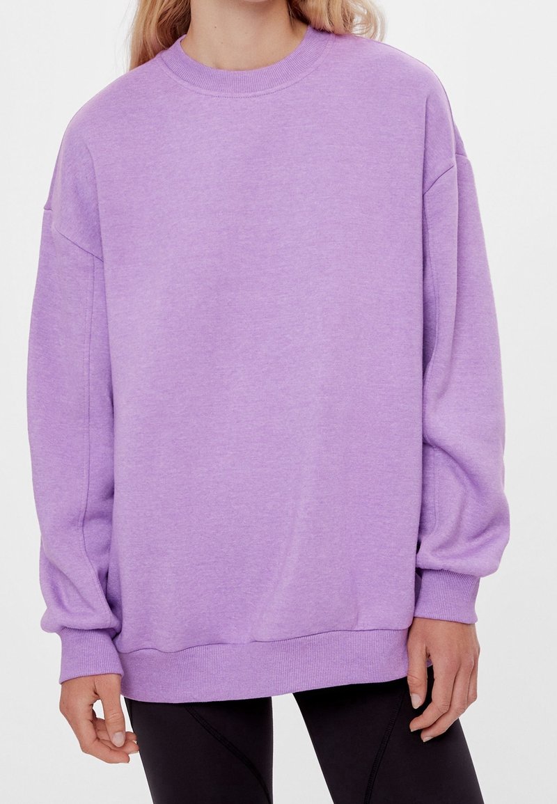 Felpa oversized lavanda con colletto a girocollo, maniche lunghe e polsini a costine. Realizzata in tessuto morbido, ha una vestibilità comoda e una texture liscia.