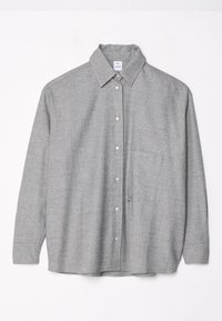 Chemise grise à boutons avec une finition texturée, manches longues, col, une poche poitrine et un accent métallique décoratif.