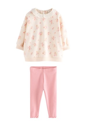 Bluza crem cu mâneci lungi, cu imprimeu floral și guler din dantelă, asortată cu colanți roz cu striații, concepută pentru un copil mic sau toddler.
