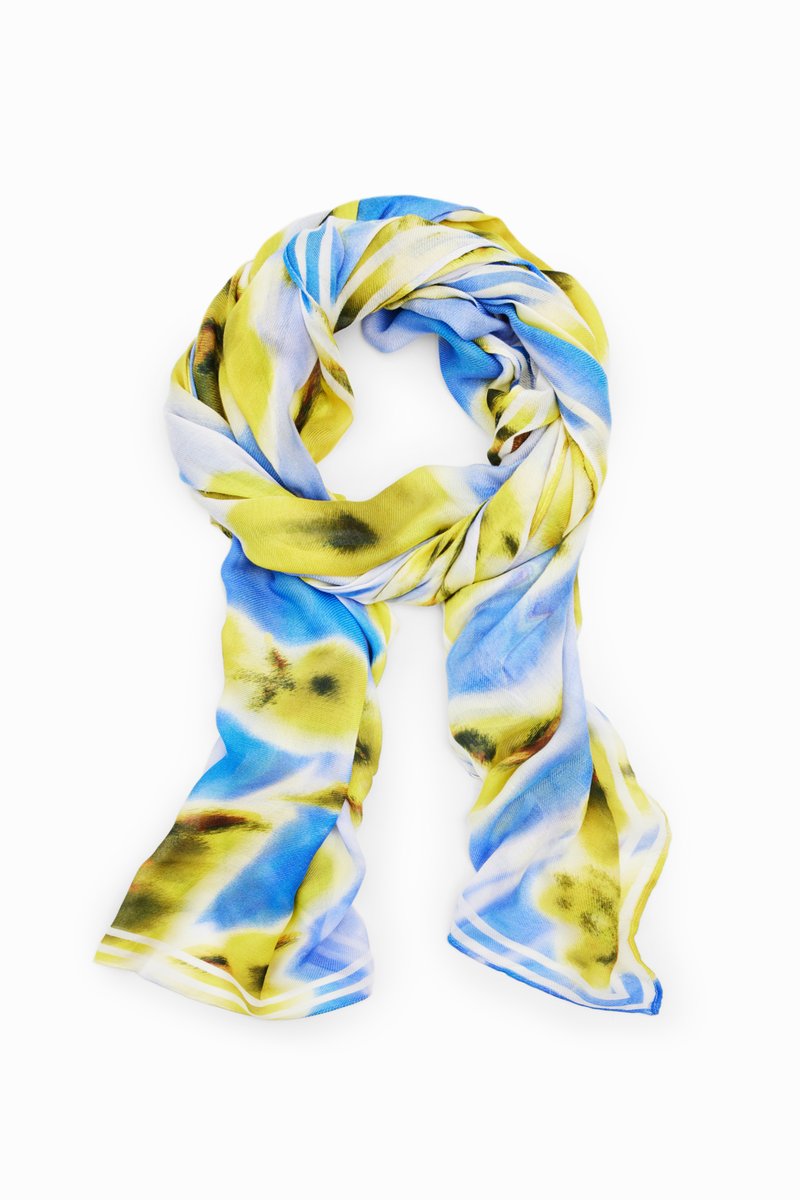 Sciarpa multicolore con un motivo astratto blu e giallo, realizzata in un tessuto leggero e morbido con una texture liscia e un design arrotolato.