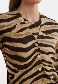 Bruine en beige cardigan met een tijgerprint, voorzien van een V-hals, lichte textuur en vijf knopen aan de voorkant.
