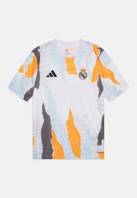 Biela športová dres s textúrovaným, abstraktným dizajnom, ktorý zahŕňa oranžové, sivé a modré vzory. Obsahuje logo Adidas a emblém Real Madrid.