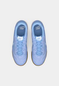 Ζευγάρι ανοιχτό μπλε αθλητικά παπούτσια Nike με κορδόνια και σόλες από καουτσούκ, απεικονιζόμενα από πάνω σε λευκό φόντο.