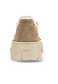 Tan-farbene Wildledersneaker mit einem weißen Kunstfellfutter, erhöhtem beigem Sohlenrand und strukturierten Details an der Sohle und Ferse.