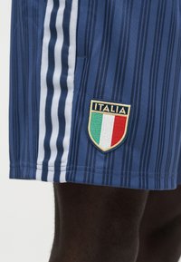 Modre športne kratke hlače z navpičnimi črtami, belimi stranskimi črtami in vezenim znakom z italijansko zastavo ter napisom "ITALIJA".