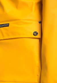 Imperméable jaune en tissu lisse, étanche, avec une poche avant et des boutons de marque ; design simple sans motifs ni accents.