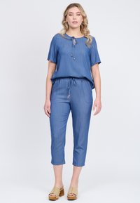 Helligblaues Zweiteiler-Outfit mit einem Top mit Kordelzug und cropped Pants. Glatte Textur, lässiges Design, kombiniert mit beigefarbenen Blockabsatzsandalen.