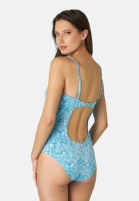 Costume da bagno di un brillante colore blu con un motivo floreale, dotato di spalline regolabili, un design con schiena scoperta e una texture del tessuto liscia.
