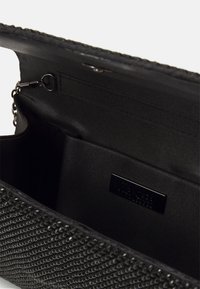 Czarny kopertówka z wnętrzem wykończonym tkaniną, małą kieszonką i widocznym metalowym zaczepem na łańcuszek.