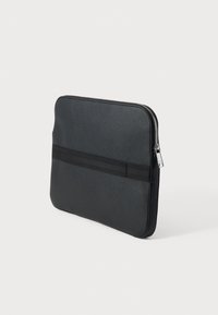 Czarny pokrowiec na laptopa o fakturowanej powierzchni, smukły, prostokątny kształt, zamek błyskawiczny oraz pozioma elastyczna opaska na froncie.