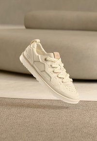 Λευκό αθλητικό παπούτσι με υφή υφάσματος στο επάνω μέρος, σχέδιο με κορδόνια και διάτρητη μύτη. Διαθέτει διακριτικό λογότυπο και ελαφρύ πάτο.