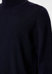 Marineblauer Strickrollkragenpullover, weiche Textur, gerippter Halsabschluss, taillierte Passform und lange Ärmel. Nahaufnahme des Stoffes und der Nähte.