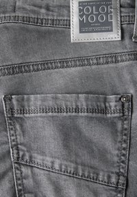 Grijze denim jeans met een gladde textuur, voorzien van een achterzak en een label met de tekst "Color Mood" in reliëf.
