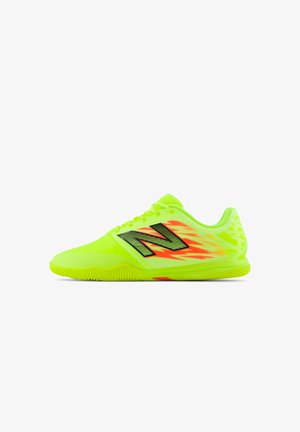 Zapatillas deportivas de color amarillo neón con acentos negros, suela texturizada y patrón de llamas asimétrico. Cuentan con cordones y un cuello acolchado.