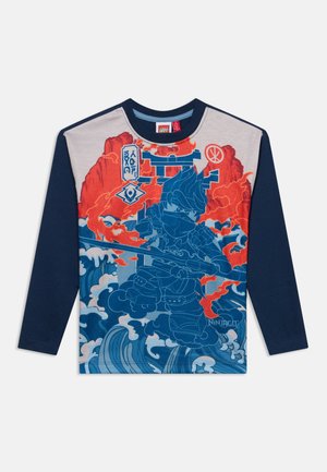 Chemise à manches longues bleu marine et gris clair avec un graphique d'un guerrier ninja bleu tenant un bâton au milieu des vagues et des flammes.