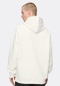 Biała bluza z kapturem, z sznurkiem, o luźnym kroju, z ribbowymi mankietami i dolnym wykończeniem, wykonana z miękkiego materiału, o gładkiej fakturze i minimalistycznym designie.