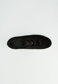 Schwarzer Wildledersneaker mit überkreuzten elastischen Schnürsenkeln und weißer Sohle, von oben gegen einen weißen Hintergrund gezeigt.