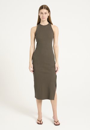 Olive green ribbed midi dress with a high neckline, sleeveless design, side slits, and a body-hugging fit. Flat sandals complete the look.