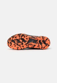 Black and orange trail running shoe sole with a textured, aggressive traction pattern, featuring black accents and a lightweight design.