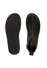 Mustat mokkanahkaiset nilkkurit sivuvetoketjulla, tasapohjaisella kuvioidulla kumipohjalla ja takana olevalla kädensilmukalla. Vuorissa on kultainen "CLARKS ORIGINALS" -merkintä.