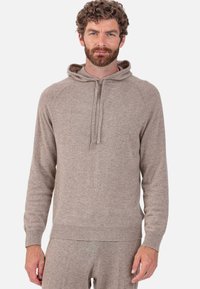 Sweat à capuche en maille texturée de couleur brun clair avec cordon de serrage, manches longues et poignets et ourlet côtelés. Coupe décontractée avec une apparence douce.