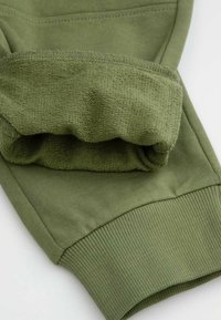 Kuf sweatshirtu w kolorze oliwkowym z prążkowaną teksturą, z gładkiego, elastycznego materiału w luźnym kroju i bezszwowym wykończeniem.